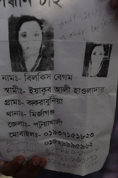 <p>SEEKING<br />[Handwritten] Rana Plaza, 7th floor, [SECTION] Quality<br />NAME: Bilkis Begum<br />HUSBAND: Yakub Ali Hawladar<br />VILLAGE: Kakrabuniya, THANA: Mirjaganj<br />DISTRICT: Patuakhali<br />MOBILE: 01937151823<br />Mo[hammad] Alamgir 01829995962<br />Mo[hammad] Abu Alam 01198097019<br />[cannot be read, beneath fingers of person holding up poster] <br />01728192671, 017349[2 digits illegible]170<br /><br /></p>